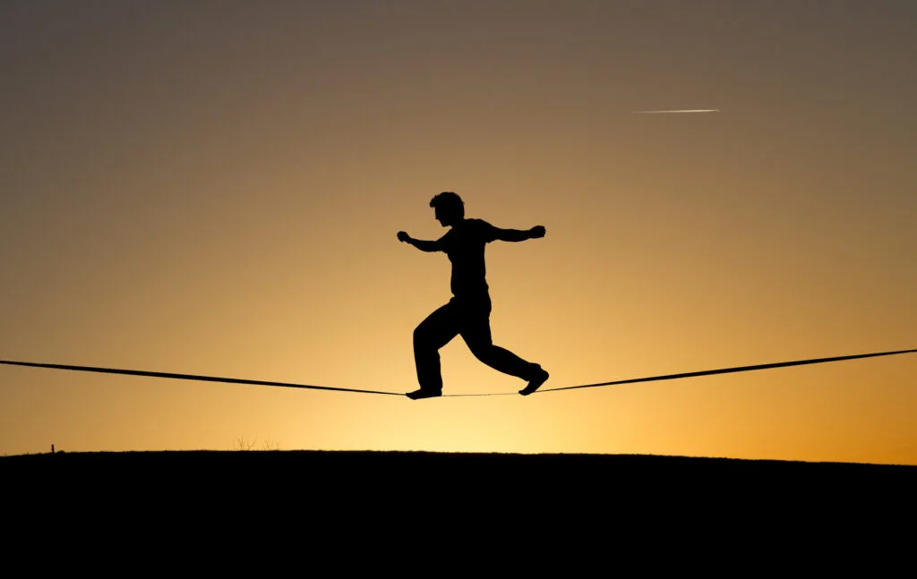 Person on a tightrope at sunset