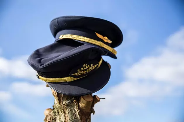 Two pilot’s caps against the sky