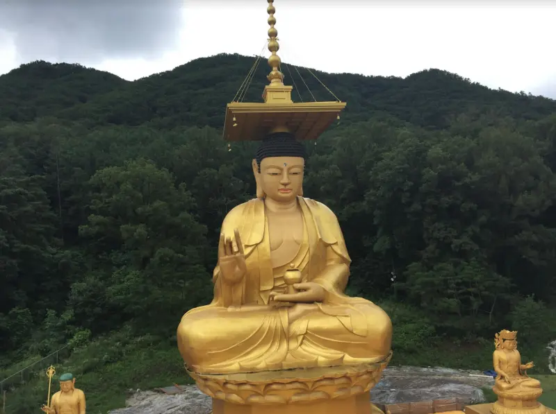 Groot verguld Boeddhabeeld tussen de beboste heuvels bij Seoul, Zuid-Korea