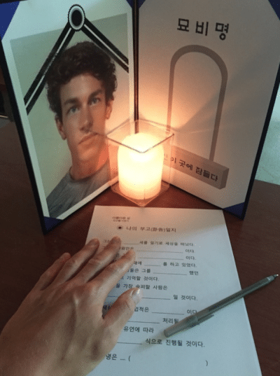A funeral portrait beside a candle and the Korean obituary form, during the coffin therapy in Seoul, a memento mori practice