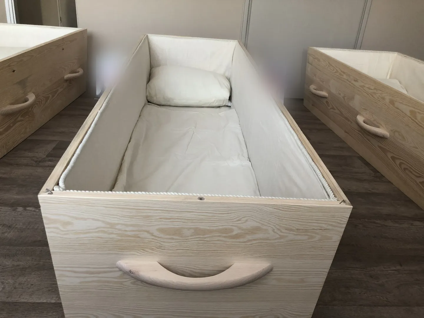 An open wooden coffin at a memento mori seminar, made up with a sheet and a pillow for a participant to lie down in